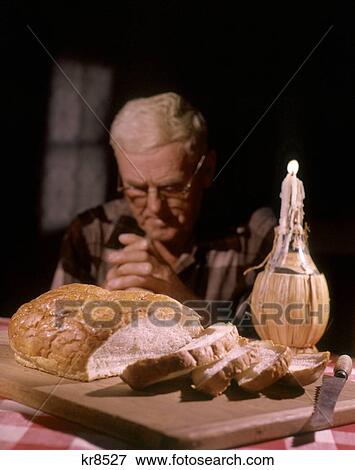 1960S Devout Senior Man Praying At Table With Candle In Wine Bottle Loaf Bread View Large Photo Image Stock Photo - 1960S Devout Senior Man Praying At Table With Candle In Wine Bottle Loaf Bread . Fotosearch