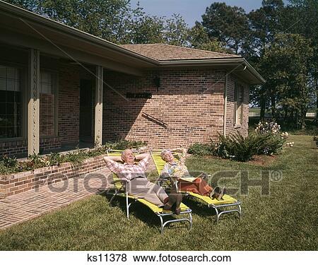 1960S Senior Couple Lawn Chairs Relaxing In Yard Of A Brick House View Large Photo Image Stock Photo - 1960S Senior Couple Lawn Chairs Relaxing In Yard Of A Brick House . Fotosearch