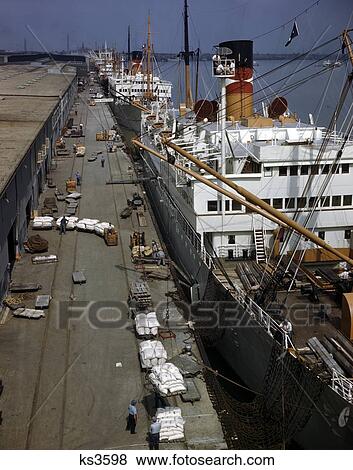 1960S Shipping Dock Mississippi River New Orleans Freighters Being Loaded With Cargo Dock Workers Longshoremen View Large Photo Image Stock Photo - 1960S Shipping Dock Mississippi River New Orleans Freighters Being Loaded With Cargo Dock Workers Longshoremen . Fotosearch