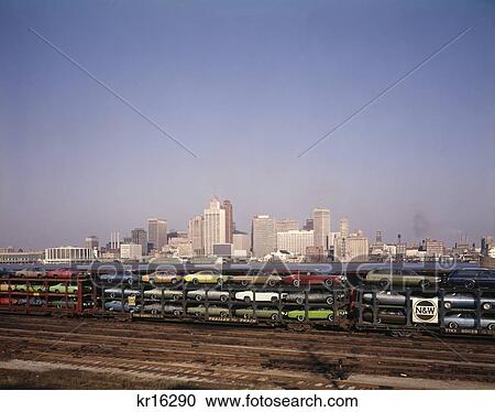 Stock Image - 1970S Freight Train Transporting Automobiles Along Detroit River And Skyline Of Detroit Michigan Usa. Fotosearch