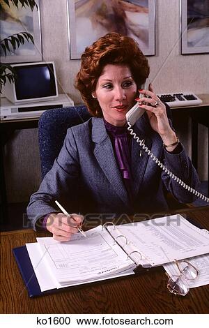 Stock Image - 1980S Businesswoman Talking On Telephone Writing In Binder . Fotosearch