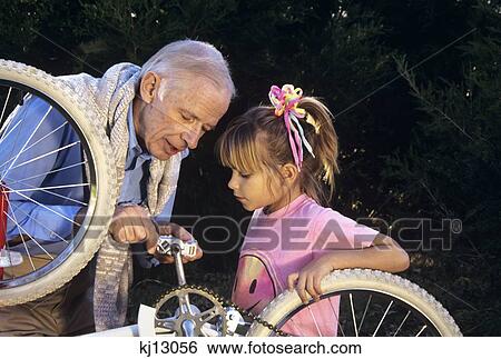 Stock Photograph - 1980S Grandfather Fixing Bike For Granddaughter . Fotosearch