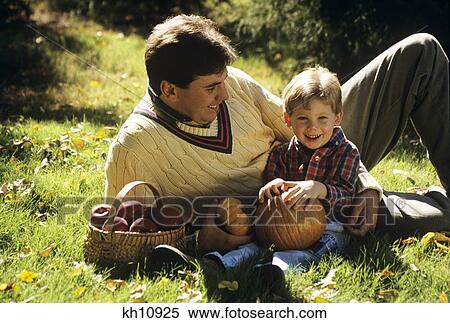 1990S Father And Son On Grass With Pumpkins And Apples View Large Photo Image Stock Photography - 1990S Father And Son On Grass With Pumpkins And Apples. Fotosearch