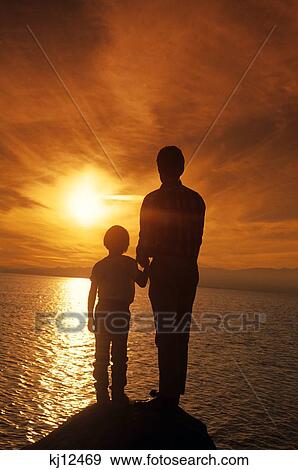 1990S Silhouetted Father And Son Watching Sunset Over Water View Large Photo Image Stock Photo - 1990S Silhouetted Father And Son Watching Sunset Over Water . Fotosearch
