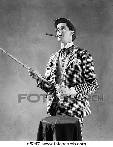 Stock Photo - 1910S 1920S Character Con Man Barker Bowler Hat Loud Vaudeville Type Clothes Pointing Cane Holding Money Smoking Cigar . Fotosearch