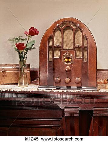 1930S Still Life Of Cathedral Style Wood Case Radio With Glass Vase Holding Red Roses And A Copper Box Sitting On Mantle Shelf View Large Photo Image Stock Photography - 1930S Still Life Of Cathedral Style Wood Case Radio With Glass Vase Holding Red Roses And A Copper Box Sitting On Mantle Shelf. Fotosearch