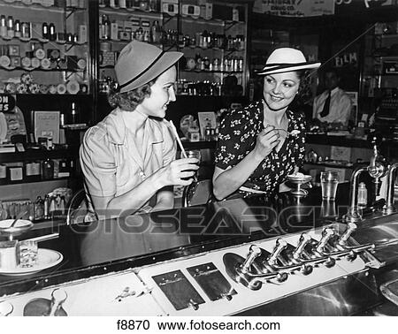 1930S Two Women Drinking Sodas Eating Ice Cream At Soda Shop Counter View Large Photo Image Stock Image - 1930S Two Women Drinking Sodas Eating Ice Cream At Soda Shop Counter. Fotosearch