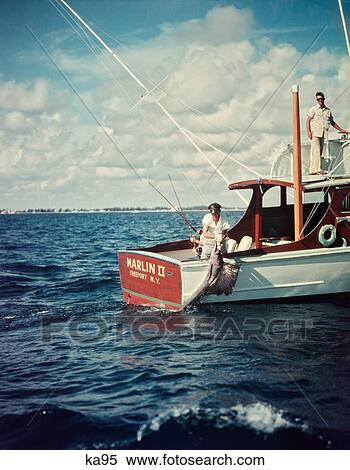 Stock Photography - 1950S Deep Sea Fishing Boat Man Pulling Aboard Captured Sailfish. Fotosearch