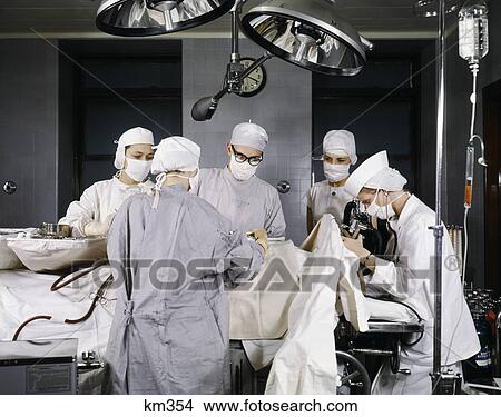 1950S Hospital Operating Room Surgery In Progress Men Women Doctors Nurses Wearing Sterile Surgical Masks Caps Gowns View Large Photo Image Picture - 1950S Hospital Operating Room Surgery In Progress Men Women Doctors Nurses Wearing Sterile Surgical Masks Caps Gowns . Fotosearch