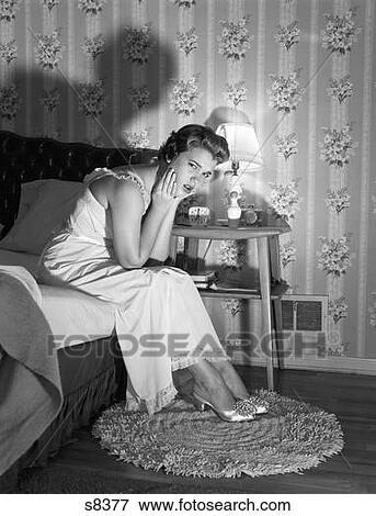 Stock Photo - 1950S Late Night Serious Upset Sleepless Woman Sitting On Edge Bed Looking At Camera Insomnia Angry Sick Worry Stressed Worried. Fotosearch
