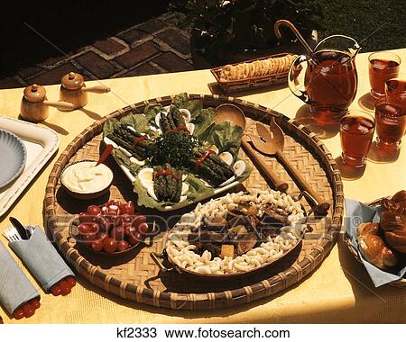 Stock Image - 1950S Platter Of Asparagus Beef Stew With Pineapple Chunks Macaroni Iced Tea Served Outdoors Picnic Table Patio . Fotosearch