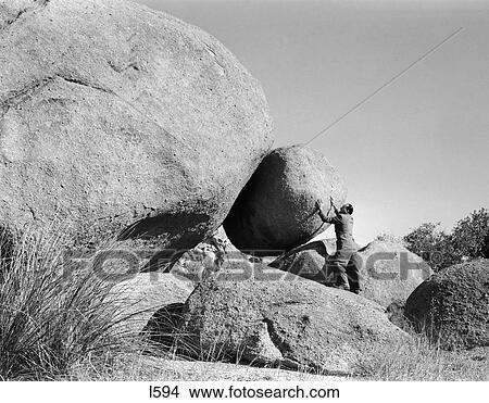 1950S Symbolic Man Outdoors Holding Back Large Boulder View Large Photo Image Picture - 1950S Symbolic Man Outdoors Holding Back Large Boulder . Fotosearch