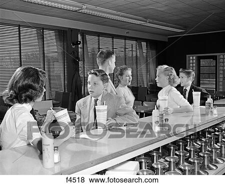 Stock Photo - 1950S Young Teenage Girls And Boys Drinking Milkshakes Sitting At Soda Fountain Counter. Fotosearch