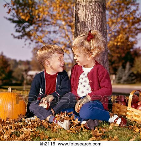 1960S Boy And Girl Smiling At One Another Sitting Under Autumn Tree With Apple Basket And Pumpkin View Large Photo Image Stock Photograph - 1960S Boy And Girl Smiling At One Another Sitting Under Autumn Tree With Apple Basket And Pumpkin. Fotosearch