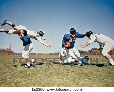 1960S Football Player Running With Ball Fending Off Potential Tackles View Large Photo Image Stock Photograph - 1960S Football Player Running With Ball Fending Off Potential Tackles . Fotosearch