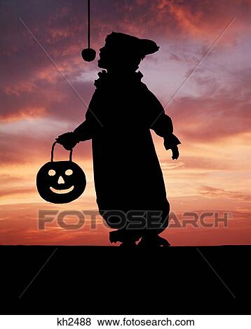 Stock Photo - 1970S Silhouette Of Child Clown Costume Carrying Pumpkin Face Trying To Bite Apple Swinging On String . Fotosearch