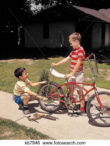 1970S Two Boys Suburban Sidewalk Repairing Bike With Cruiser Handlebars And Stingray Banana Seat View Large Photo Image Stock Photograph - 1970S Two Boys Suburban Sidewalk Repairing Bike With Cruiser Handlebars And Stingray Banana Seat . Fotosearch