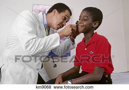 1980S African American Doctor Examining Ear Of Smiling Boy Patient View Large Photo Image Stock Photo - 1980S African American Doctor Examining Ear Of Smiling Boy Patient . Fotosearch