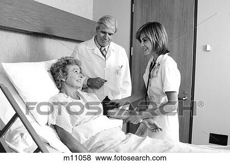 1980S Elderly Woman In Hospital Bed Having Blood Pressure Taken By Female Nurse Male Doctor Standing Beside Her View Large Photo Image Stock Photo - 1980S Elderly Woman In Hospital Bed Having Blood Pressure Taken By Female Nurse Male Doctor Standing Beside Her . Fotosearch