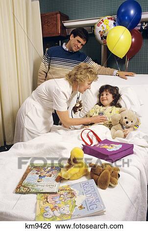 Stock Photograph - 1980S Father Watches Nurse Examine Daughter In Hospital Bed . Fotosearch