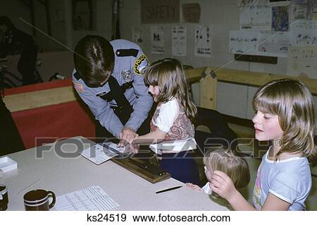 Stock Photo - 1980S Police Officer Finger Printing Little Girl At Safety Fair . Fotosearch