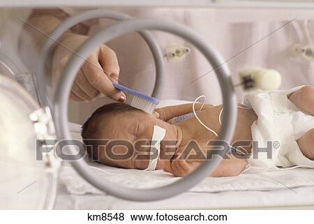 Stock Photo - 1980S Premature Infant Has Hair Brushed In Neo-Natal Unit Of Hospital . Fotosearch