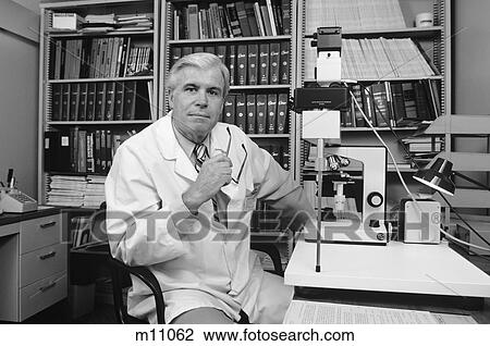 1980S Senior Male Doctor Sitting At Desk Behind Microscope Glasses Removed Turned Looking At Camera View Large Photo Image Stock Image - 1980S Senior Male Doctor Sitting At Desk Behind Microscope Glasses Removed Turned Looking At Camera. Fotosearch
