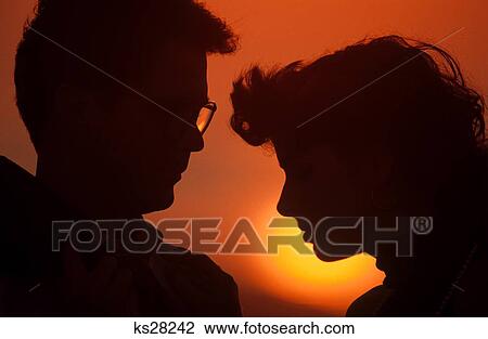 1980S Sunrise Or Sunset Silhouette Of Heads Of Anonymous Serious Young Adult Couple In Profile View Large Photo Image Stock Image - 1980S Sunrise Or Sunset Silhouette Of Heads Of Anonymous Serious Young Adult Couple In Profile . Fotosearch
