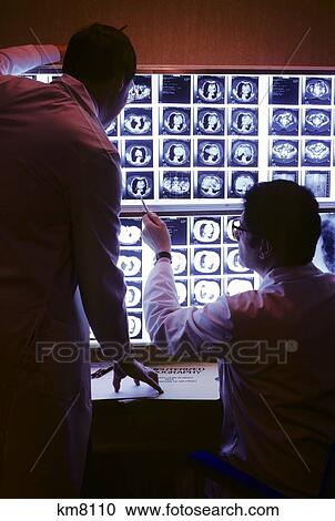 Stock Image - 1980S Two Doctors Examining Cat Scan Films Of Chest . Fotosearch