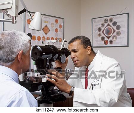 optometrist 1990s african american examining older eyes man fotosearch