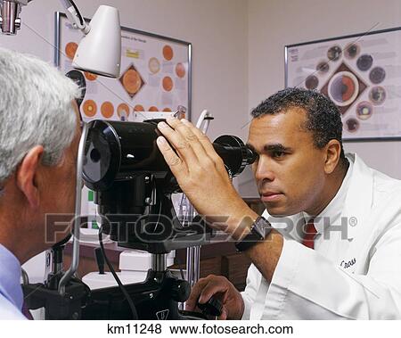 Stock Photo - 1990S African American Optometrist Examining Older Man'S Eyes . Fotosearch