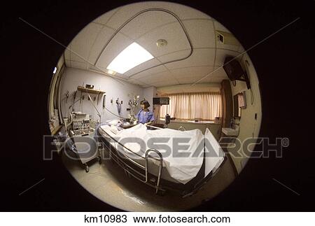 Stock Image - 1990S Fisheye Lens View Of Nurse Tending Patient In Intensive Care Unit Room. Fotosearch