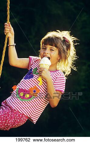 Stock Image - 1990S Girl On Tire Swing Eating Ice Cream Cone . Fotosearch