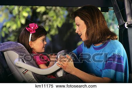 Stock Photography - 1990S Mother Putting Daughter In Child Car Seat . Fotosearch