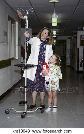 1990S Nurse Walking Down Hospital Hallway Pushing An Iv Drip Pole Connected To A Little Girl View Large Photo Image Stock Image - 1990S Nurse Walking Down Hospital Hallway Pushing An Iv Drip Pole Connected To A Little Girl . Fotosearch