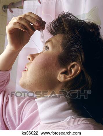 Stock Image - 1990S Young Woman Giving Herself Eyedrops . Fotosearch