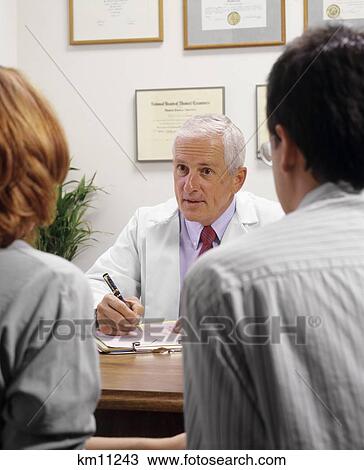 Stock Image - Male Physician Talking With Anonymous Couple In Office. Fotosearch