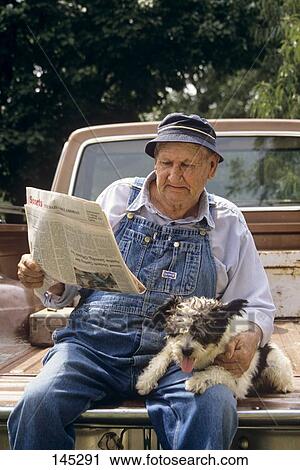 Man Sitting On The Back Of A Pickup Reading A Newspaper Wearing Bib Overalls Holding A Dog View Large Photo Image Stock Image - Man Sitting On The Back Of A Pickup Reading A Newspaper Wearing Bib Overalls Holding A Dog . Fotosearch