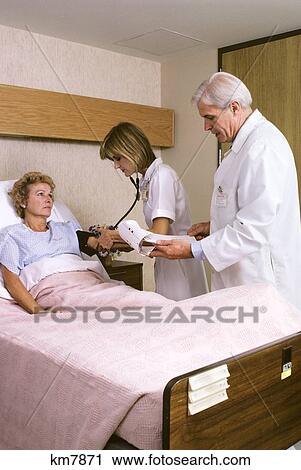 Mature Female Patient In Hospital Bed Nurse And Doctor Taking Vitals Visiting View Large Photo Image Stock Image - Mature Female Patient In Hospital Bed Nurse And Doctor Taking Vitals Visiting. Fotosearch