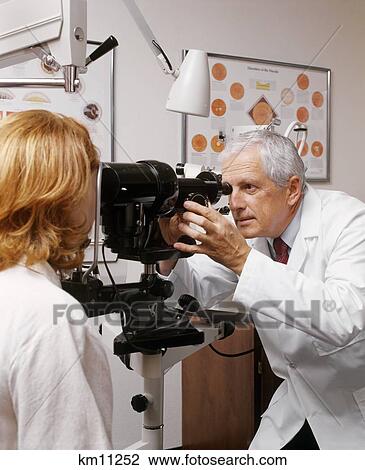 Stock Image - Older Optometrist Examining Woman'S Eyes . Fotosearch