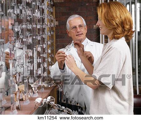 Picture - Older Optometrist Showing Glasses To Woman . Fotosearch