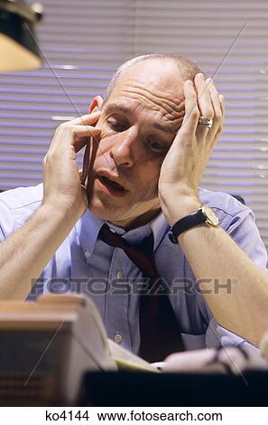 Stressed Businessman At Desk Holding Head In Hands Smoking A Cigarette View Large Photo Image Picture - Stressed Businessman At Desk Holding Head In Hands Smoking A Cigarette. Fotosearch