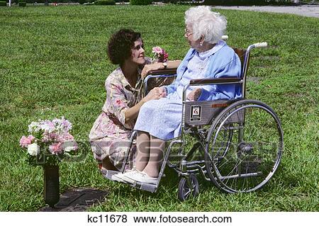 Stock Photo - Two Women Young And Old Placing Flowers On Loved One'S Grave. Fotosearch