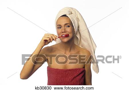 Stock Image - Woman Towel On Head And Around Torso Brushing Her Teeth Looking At Camera. Fotosearch