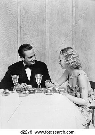 1930S Couple Man Woman Formal Dress Tuxedo Sitting Table Romantic Dinner Romance Crystal Goblets Date View Large Photo Image Stock Photo - 1930S Couple Man Woman Formal Dress Tuxedo Sitting Table Romantic Dinner Romance Crystal Goblets Date . Fotosearch