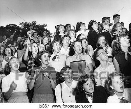 1950S Group Boys Girls Teens Crowd Standing Cheering Watching High School Football Game View Large Photo Image Stock Photo - 1950S Group Boys Girls Teens Crowd Standing Cheering Watching High School Football Game. Fotosearch