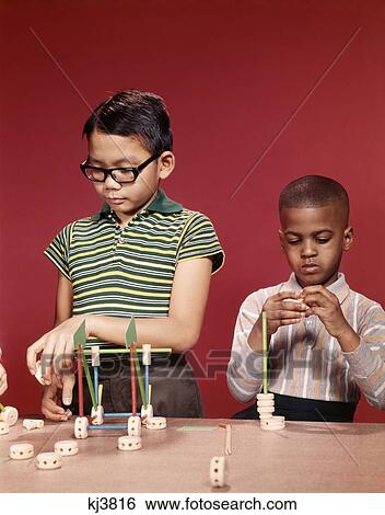 1960S African American And Asian Boy Working Playing Together With Tinker Toys View Large Photo Image Stock Photograph - 1960S African American And Asian Boy Working Playing Together With Tinker Toys . Fotosearch