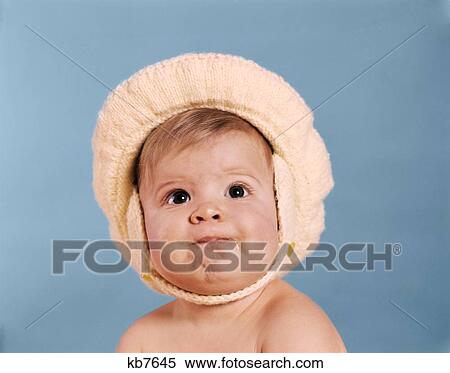 Stock Photography - 1960S Baby Wearing Yellow Knit Hat Looking At Camera. Fotosearch