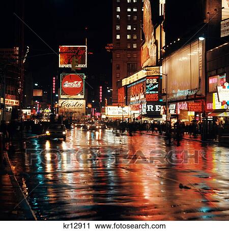 Stock Image - 1960S Circa 1967 Wet Street And Neon Lights At Night Times Square Manhattan New York City Usa. Fotosearch