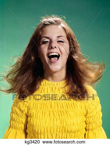 Stock Image - 1960S Laughing Young Teenage Woman Tossing Her Long Brown Hair Looking At Camera. Fotosearch
